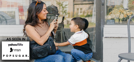 Mom wearing the Jetsetter Mini Diaper Bag on a park outing, showing the compact size and hands-free design editors love.