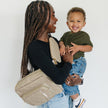 A mom waring diaper bag and holding her baby