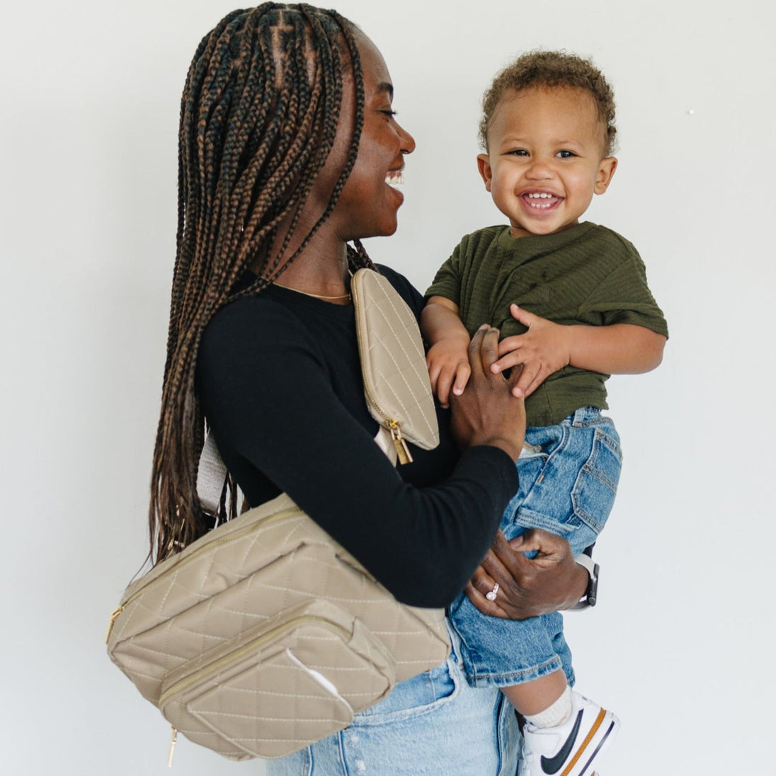 A mom waring diaper bag and holding her baby