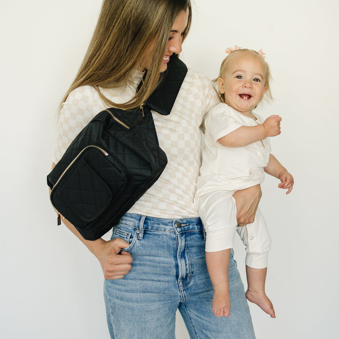 a mother wearing black crossbag and holding her baby 